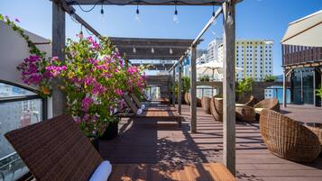 Eine Dachterrasse mit Holzboden, Korbmöbeln und Blumentöpfen.