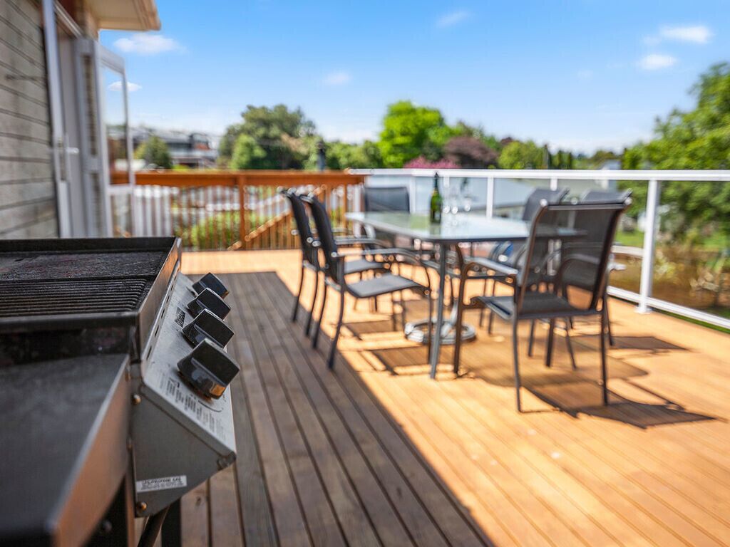 A wooden deck with a grill, outdoor table, and chairs.