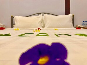 Una habitación de hotel con una cama bien tendida, ropa de cama blanca y un cabecero de metal.