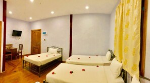 Habitación de hotel con dos camas individuales, un escritorio con silla, un televisor en la pared y una puerta de madera.