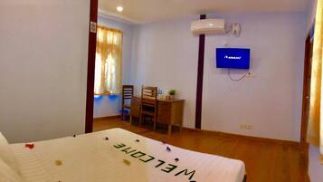 Een hotelkamer met een bed, een bureau, een stoel, een televisie en een airconditioning.