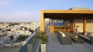 Una terraza en la azotea con zona de estar, comedor y vistas a la ciudad.