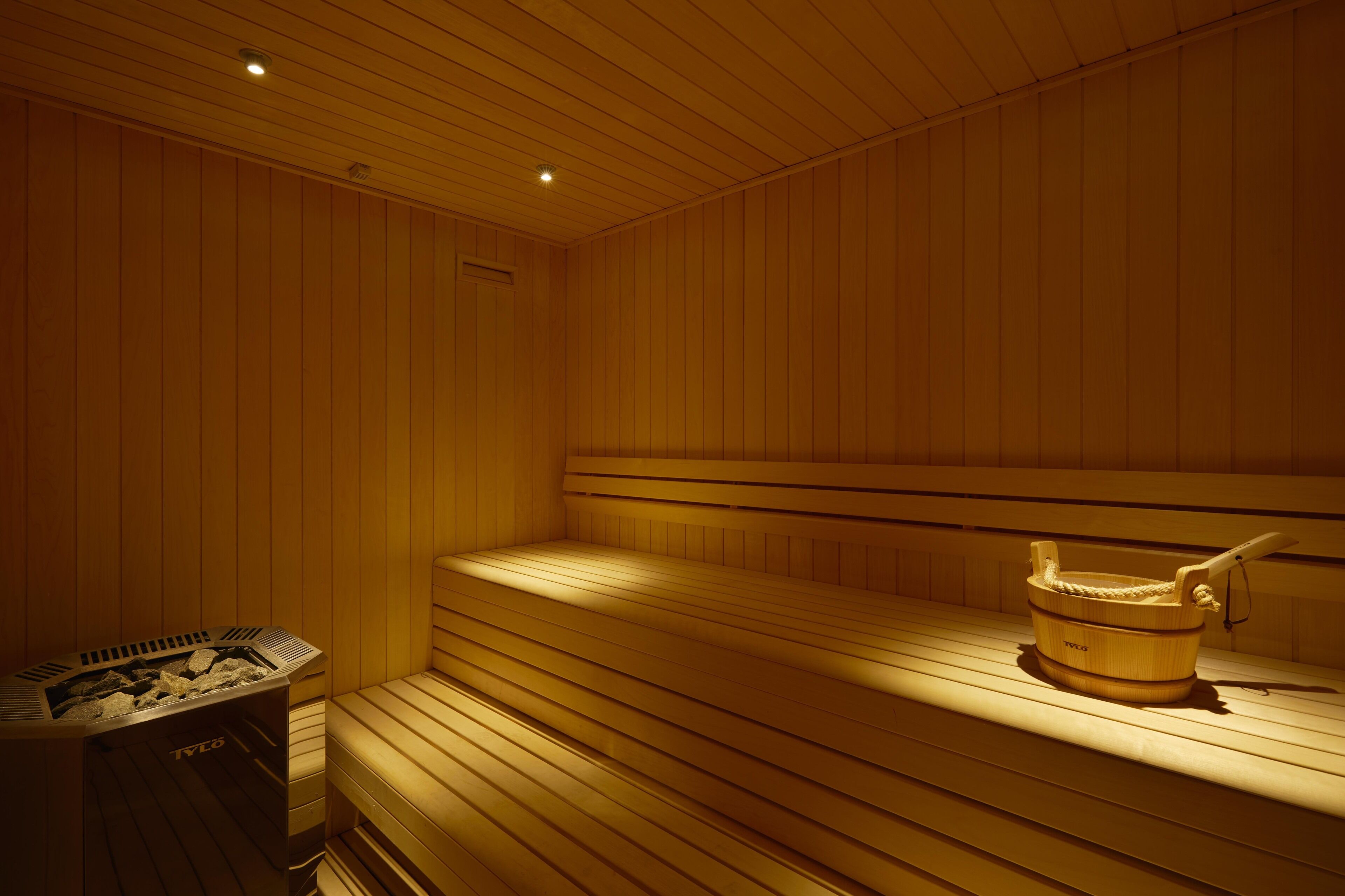 A sauna with wooden benches and a wooden bucket.