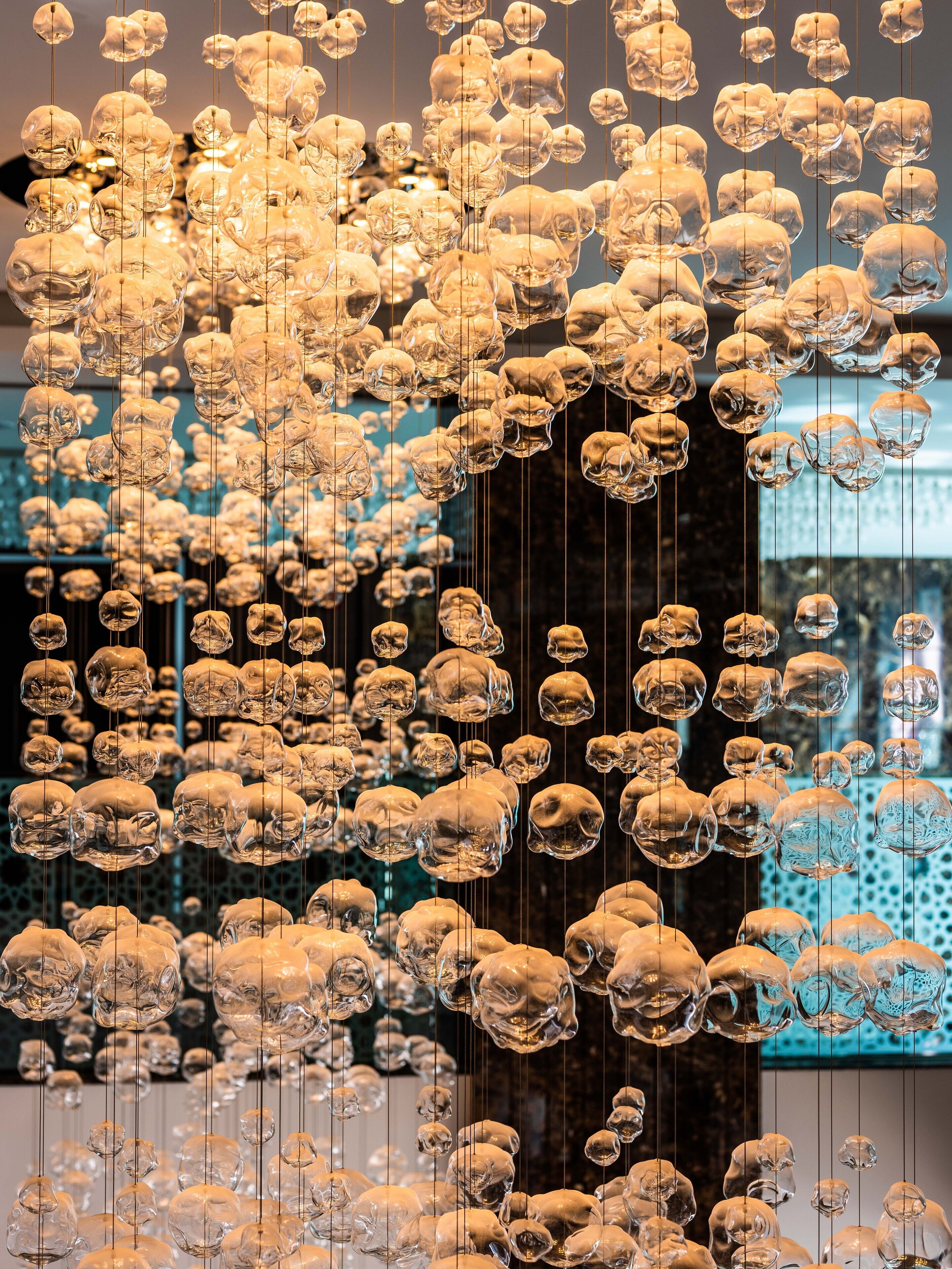 A large number of hanging glass sculptures in a modern art installation.