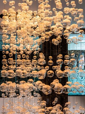 A large number of hanging glass sculptures in a modern art installation.