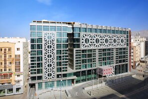 A modern building with a geometric facade, a prominent entrance, and a clear sky.