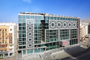 A modern building with a geometric facade, a prominent entrance, and a clear sky.