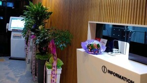 A reception area with a wooden panel wall, a reception desk labeled "INFORMATION", and a digital kiosk. - 1Beonji Muintel (Gwangyang)