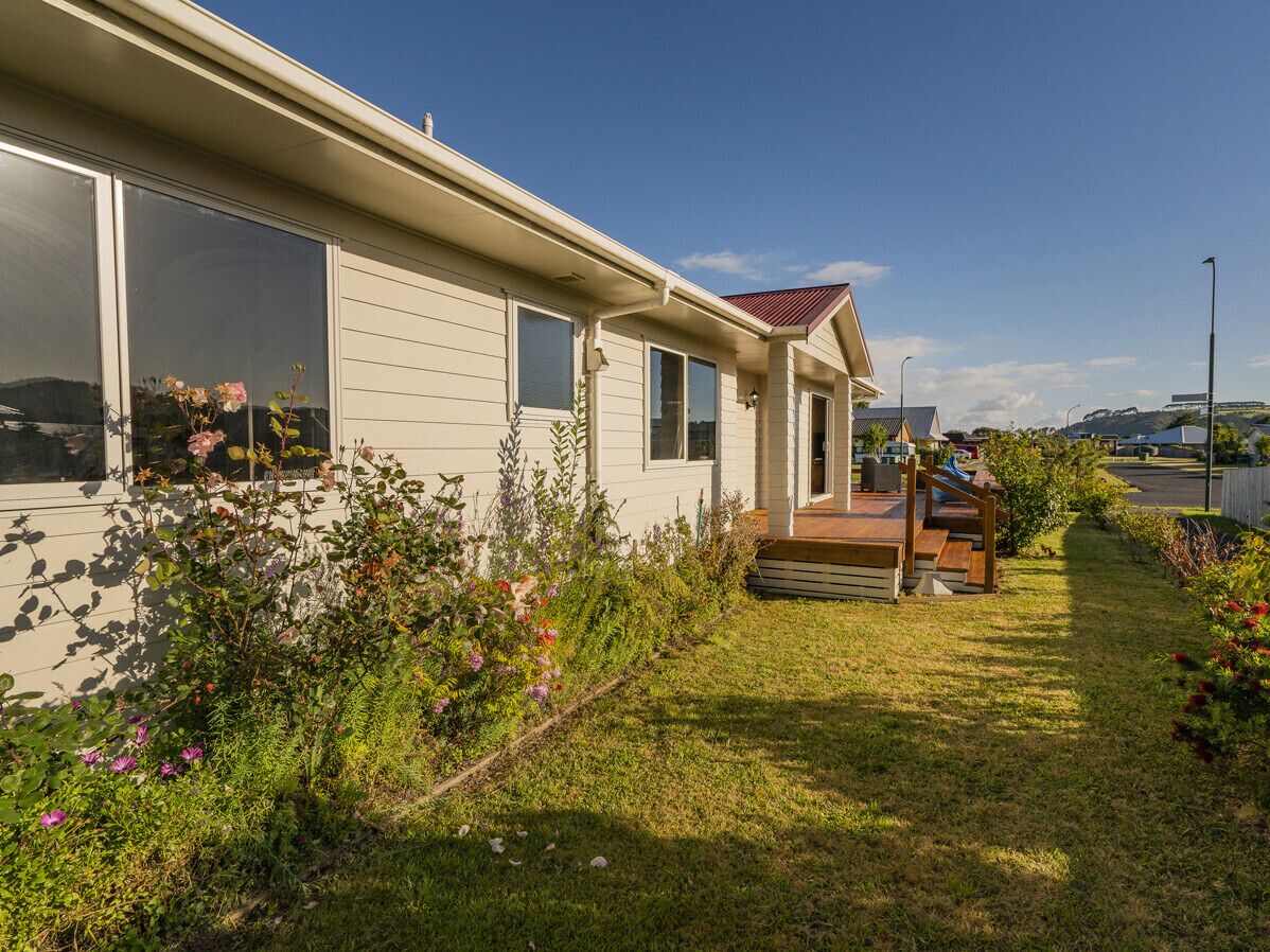 A single-story house with a front porch, a small deck, and a well-maintained garden with various plants and flowers.