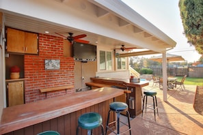 Un espace bar extérieur avec un mur en briques, un comptoir en bois et des sièges.
