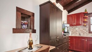 Una cocina con un armario de madera, una mesa de comedor con una botella de vino y un televisor.