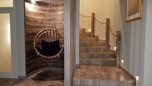 Een houten trap met een hangstoel en een lijst met een foto aan de muur.