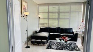Ein modernes Wohnzimmer mit einem schwarzen Ledersofa, einem Glastisch und einem gemusterten Teppich.