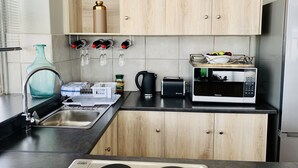 Eine moderne Küche mit Spüle, Mikrowelle und einem Schrank mit Weinkühler darüber.