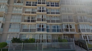 Edifício moderno com vários andares, apresentando varandas e amplas janelas.