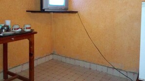 A small room with a television on a shelf, a table with cups, and a whiteboard.