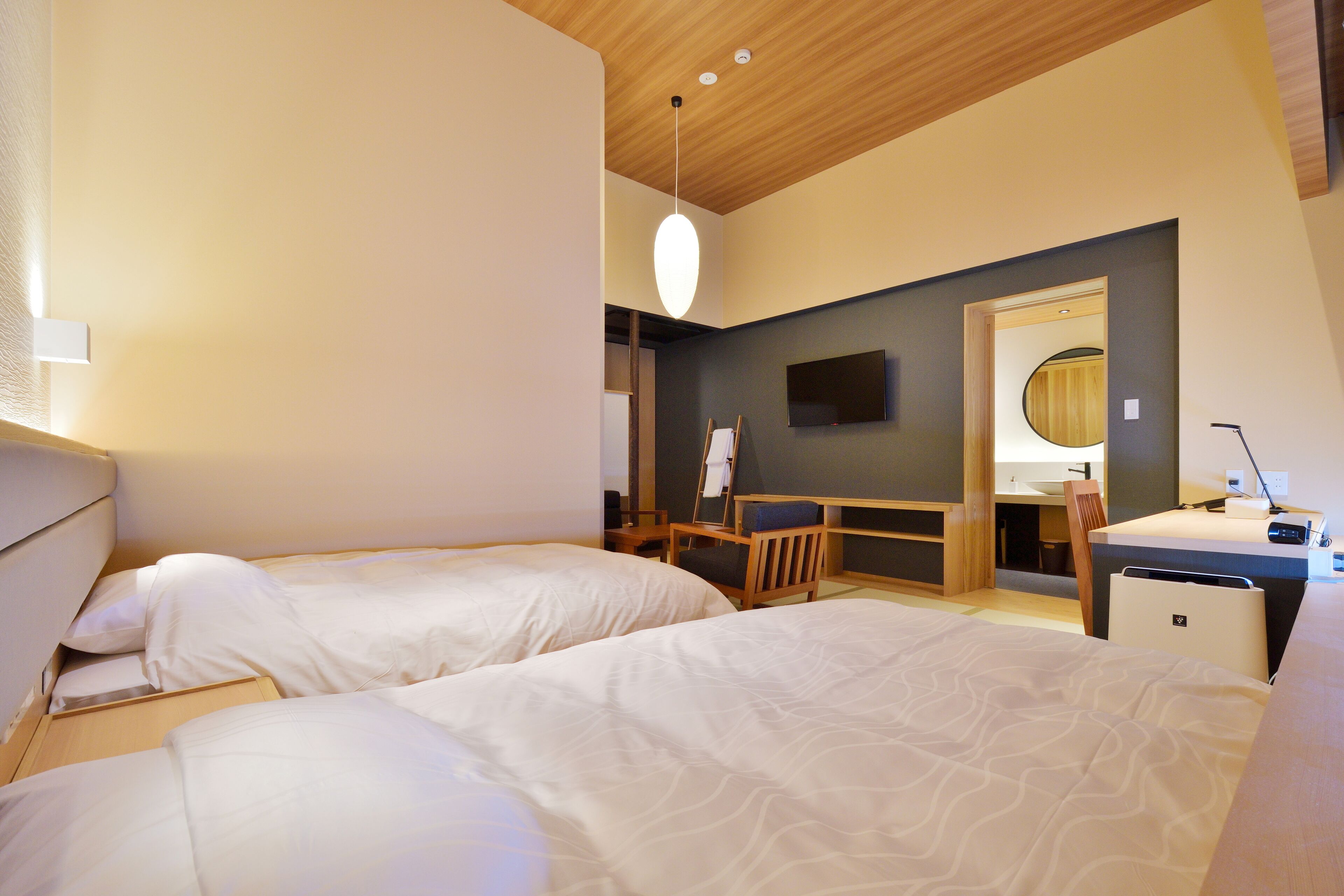 Habitación de hotel con dos camas, un escritorio, una silla, un televisor y un espejo.
