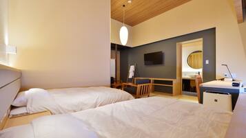 Habitación de hotel con dos camas, un escritorio, una silla, un televisor y un espejo.