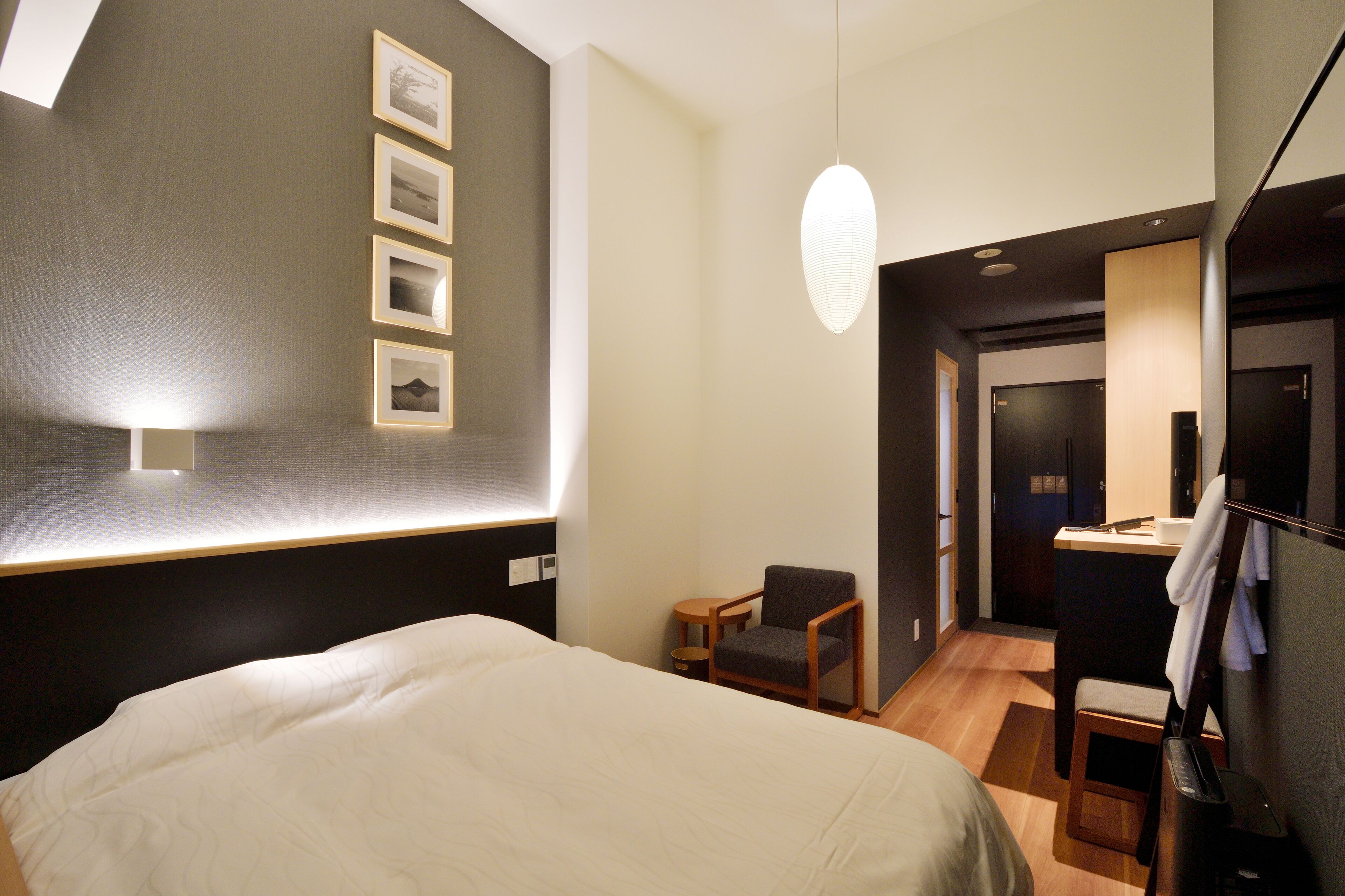 Una habitación de hotel con una cama grande, un escritorio pequeño, una silla y un televisor instalado en la pared.