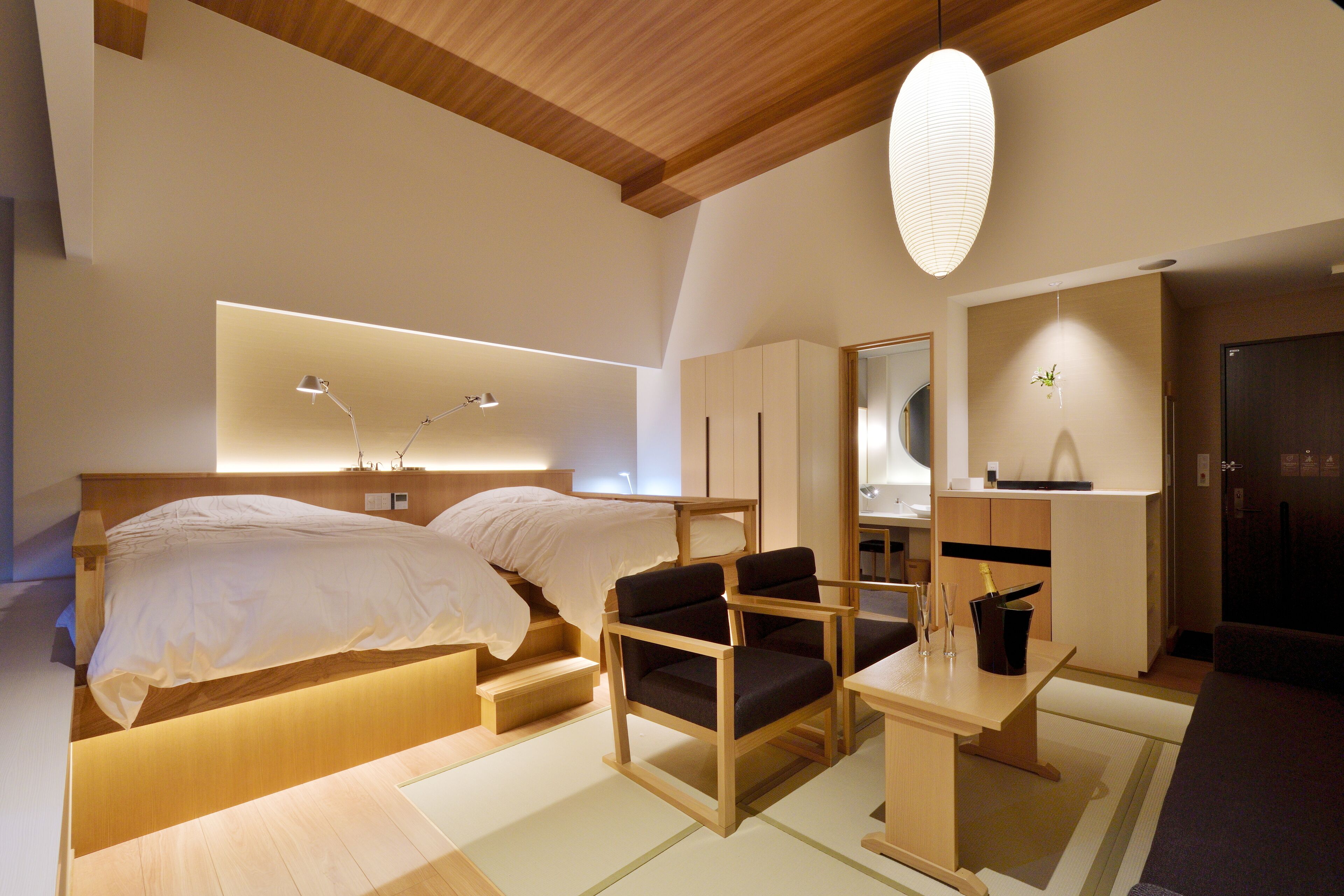Ein modernes Schlafzimmer mit einem Bett, zwei Stühlen, einem Schreibtisch und einem Spiegel.