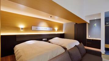 A modern hotel room with two beds, a sofa, a wall-mounted TV, and a built-in wardrobe.