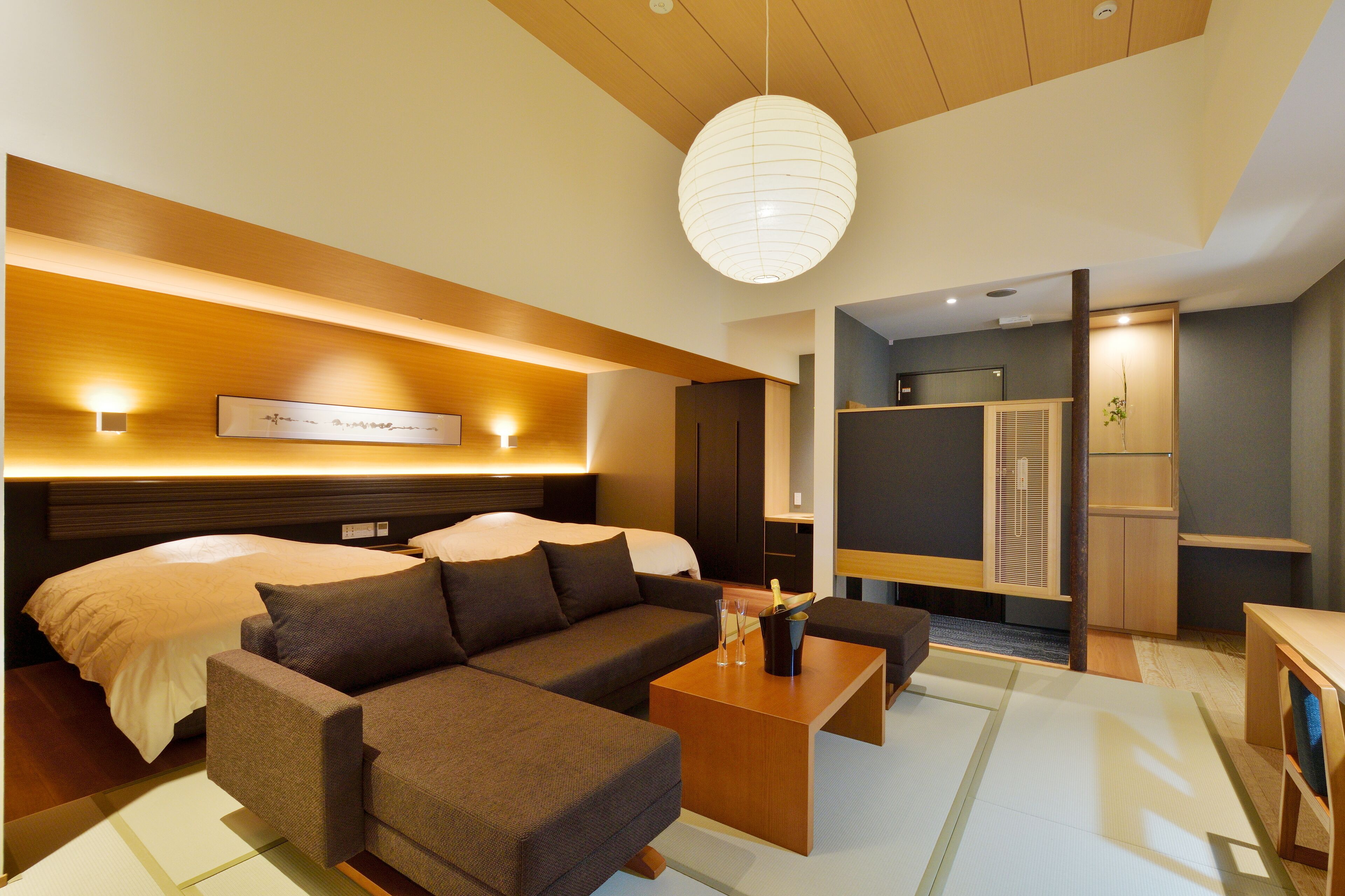 A modern hotel room with a large bed, a sofa, a coffee table, and a dining area.