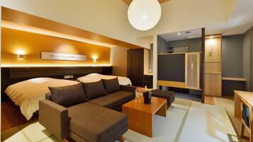 A modern hotel room with a large bed, a sofa, a coffee table, and a dining area.