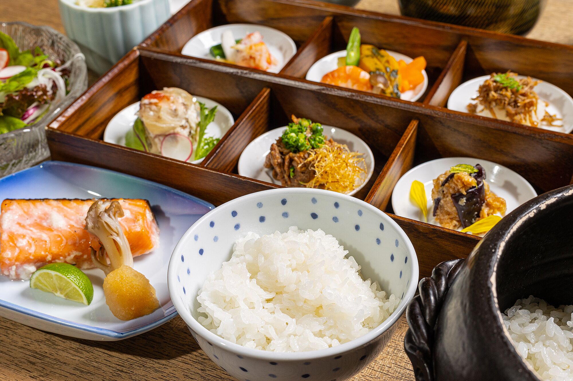 Una comida tradicional japonesa con diversos platos, incluyendo salmón, arroz y verduras.