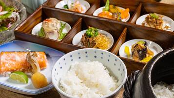 Una comida tradicional japonesa con diversos platos, incluyendo salmón, arroz y verduras.