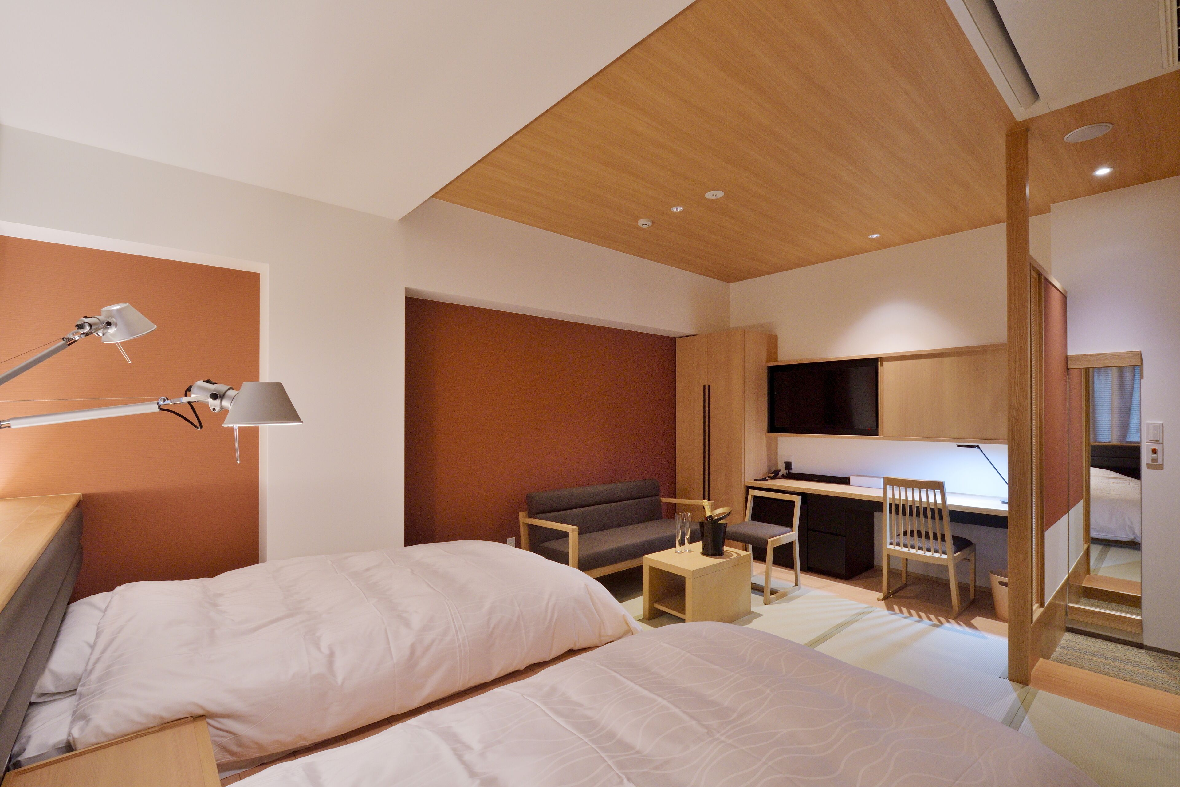 A modern hotel room with a bed, desk, chair, and a television.