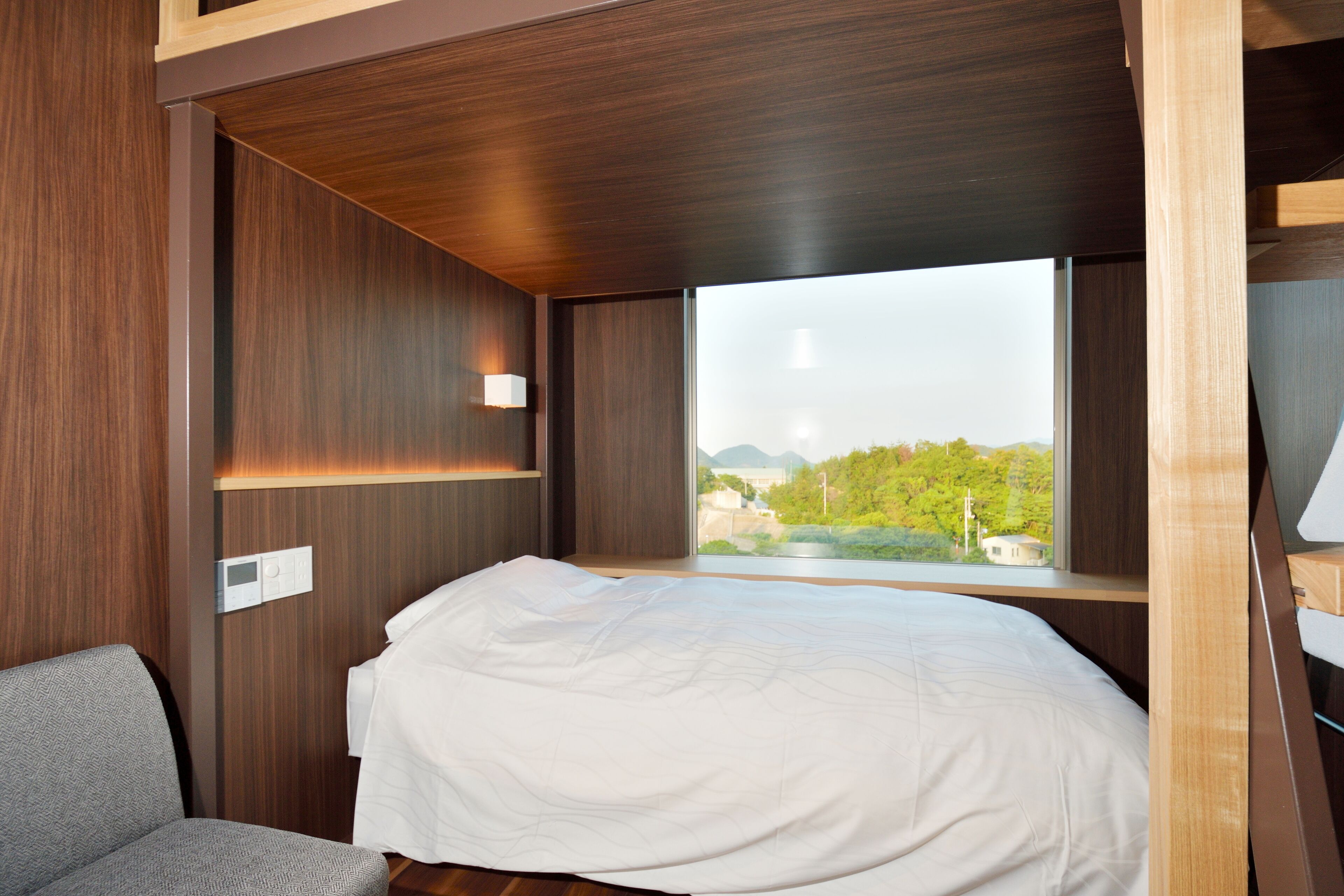 Une chambre à coucher avec un lit, une fenêtre et une vue sur la verdure et les bâtiments.