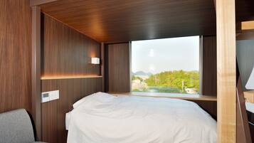 Une chambre à coucher avec un lit, une fenêtre et une vue sur la verdure et les bâtiments.