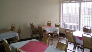 A dining area with tables and chairs, a ceiling with beams, and a window with blinds. - Silver Hotel Kisumu (Kisumu)