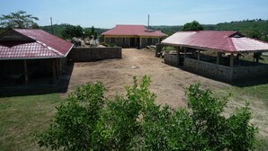 A rural property with multiple buildings, including a main house with a red roof and several smaller structures with similar roofing. - Cawaal Hotels (Kisumu)