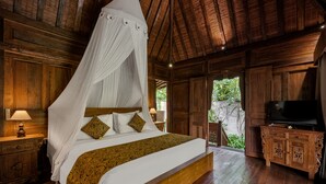 A wooden four-poster bed with a canopy, a television on a wooden cabinet, and a nightstand with a lamp. - Andara Ubud Villa (Ubud)