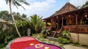 A tropical resort with a wooden building, a landscaped garden, and a heart-shaped flower bed. - Andara Ubud Villa (Ubud)