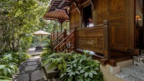 A wooden building with intricate carvings, a stone pathway, and lush greenery. - Andara Ubud Villa (Ubud)