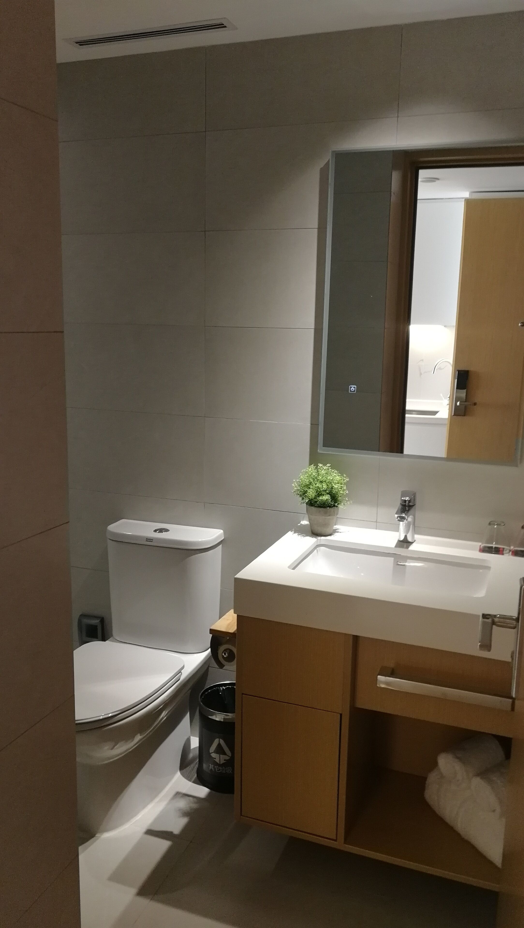 Un baño moderno con inodoro, lavamanos y espejo.