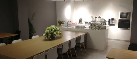 A modern kitchen with a central island, white chairs, and a dining table.