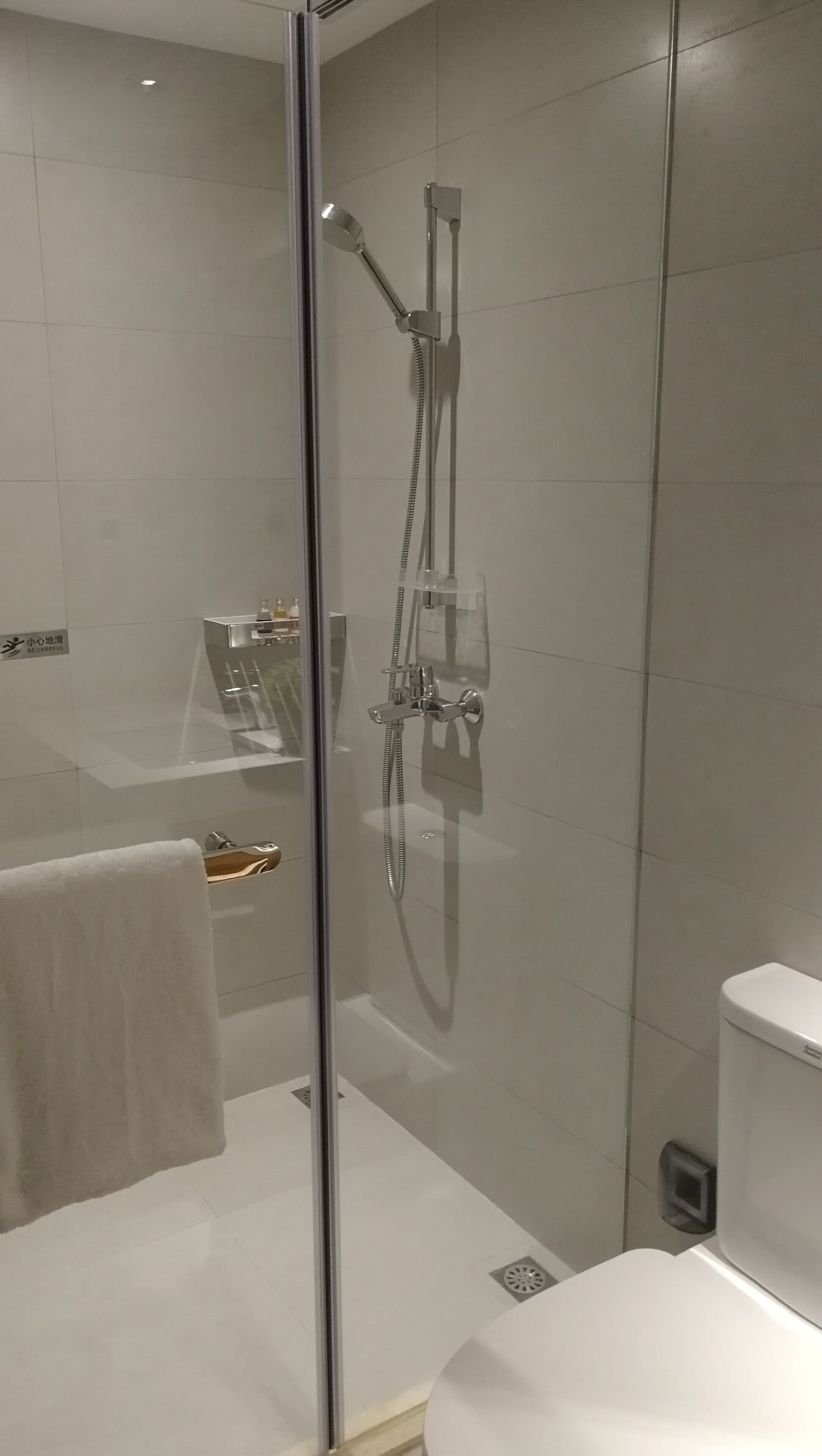 A modern bathroom with a glass-enclosed shower, a white sink, and a toilet.