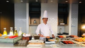 A chef in a white uniform and hat cooking at a buffet counter with various dishes and condiments. - LN Residence Guangzhou Changdi - Free shuttle between hotel and Exhibition Center during Canton Fair (Guangzhou)