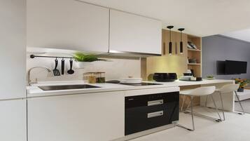 A modern kitchen with a white countertop, black appliances, and a built-in oven. There are two white bar stools and a potted plant.