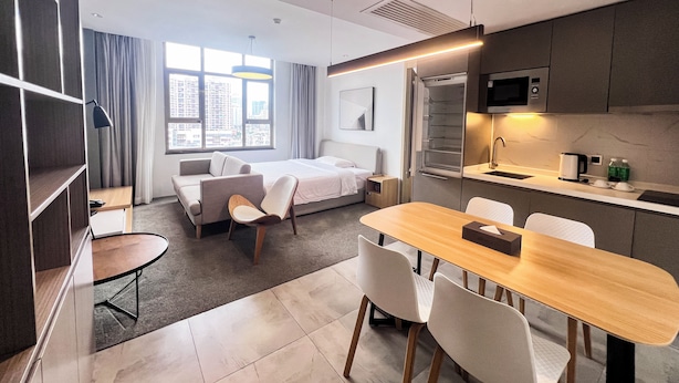A modern hotel room with a bed, a small sitting area, a dining table, and a kitchenette. - LN Residence Guangzhou Changdi - Free shuttle between hotel and Exhibition Center during Canton Fair (Guangzhou)