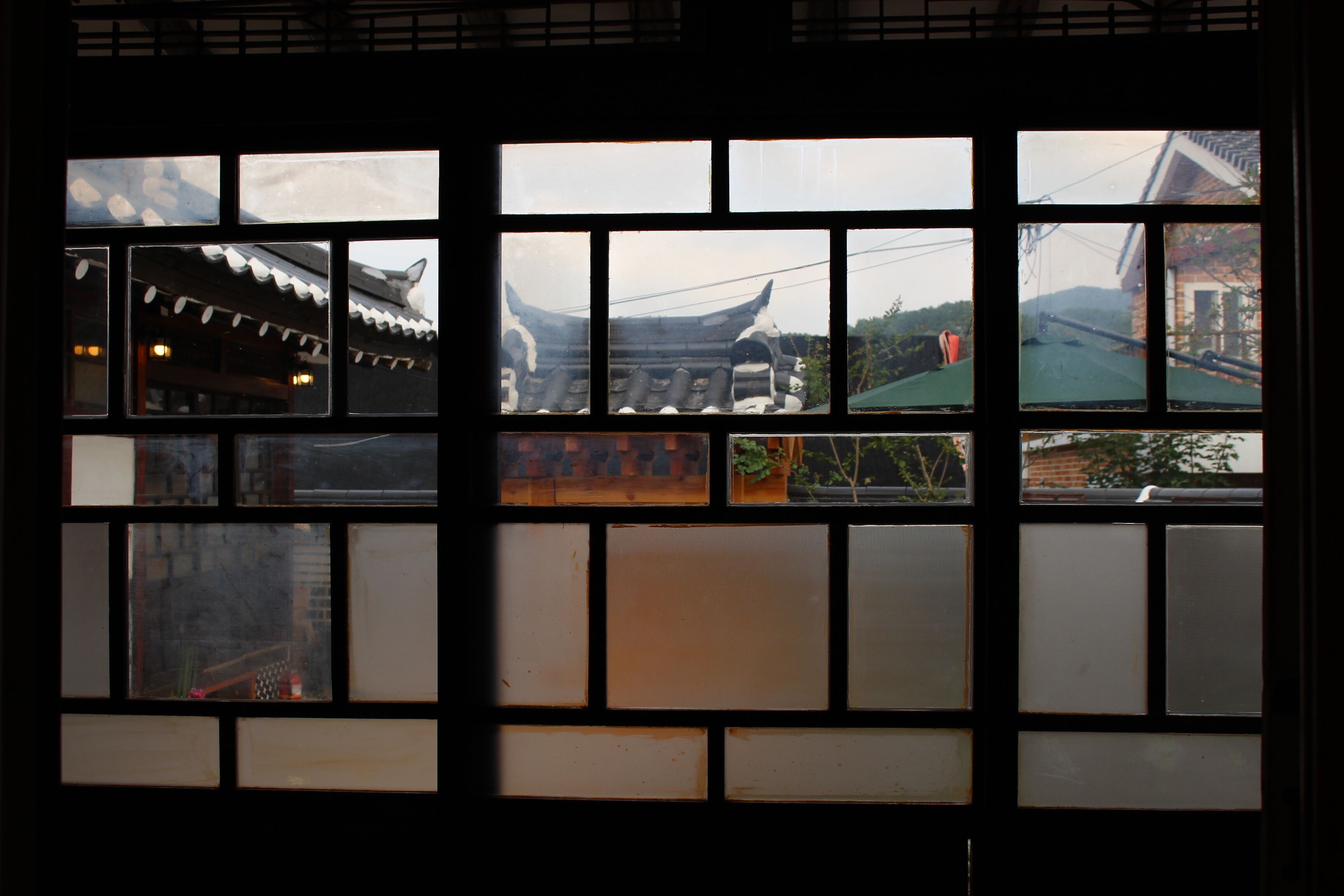 A window with multiple panes, some of which display views of traditional architecture and a bridge.