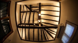 Un escalier en colimaçon avec des poutres en bois et un luminaire central.