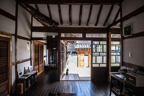 A traditional Japanese interior with tatami flooring, wooden beams, sliding doors, and a view of the outside. - BongHwangJae Hanok (Gongju)