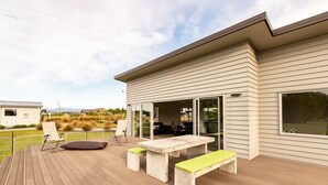 Una casa moderna con terraza, una mesa de patio y un banco.