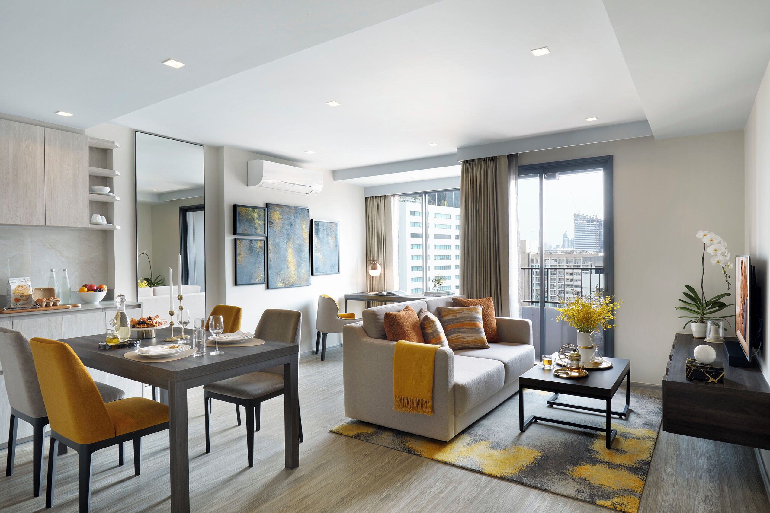 A modern living room with a dining area, a sofa set, a coffee table, and a view of the city through large windows.