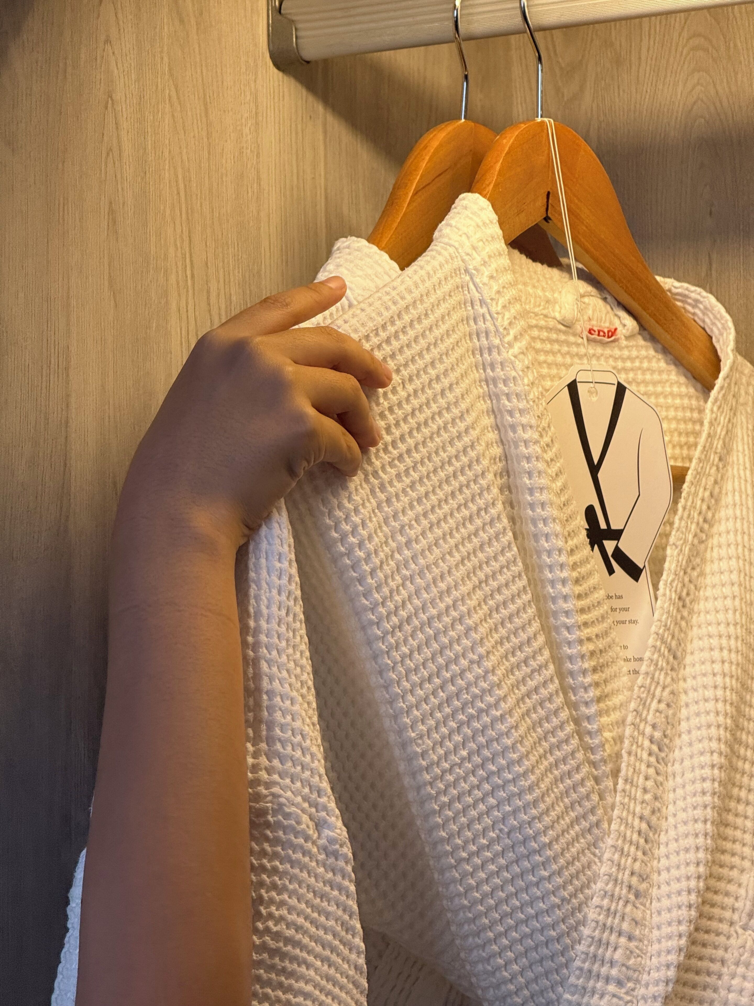 A white knitted garment hanging on a wooden hanger.