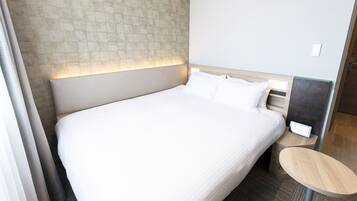A hotel room with a large bed, a bedside table, and a headboard with a light panel.